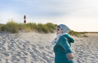 Deutschland, Sylt, Nordsee, Frau spaziert am Sandstrand - MKFF00493