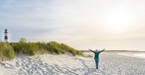 Deutschland, Sylt, Nordsee, glückliche Frau spaziert am Sandstrand - MKFF00494