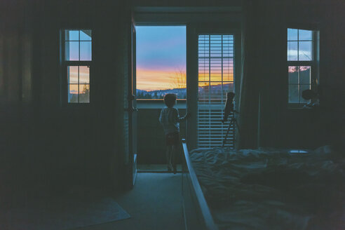 Kleiner Junge steht in der Zimmertür und beobachtet den Sonnenuntergang - CMSF00043