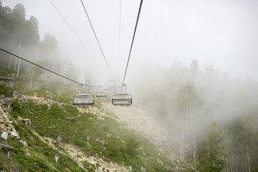 Russland, Sotschi, leere Seilbahn im bewölkten Wald - EYAF00092