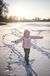 Portrait of little girl standing on snow field - EYAF00096