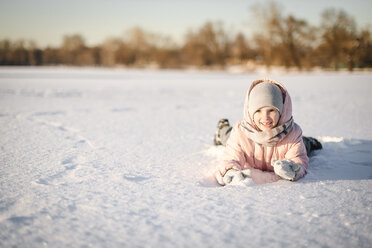 Portrait of little girl lying in snow field - EYAF00097