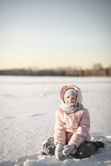 Porträt eines kleinen Mädchens, das im Schneefeld sitzt - EYAF00099