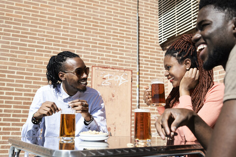 Drei glückliche Freunde trinken Bier in einer Bar im Freien, lizenzfreies Stockfoto