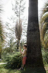 Boy leaning against a palm tree - EYAF00103