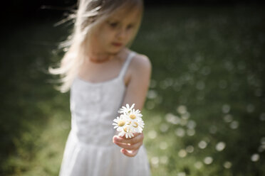 Little girl holding flowers in field - EYAF00107