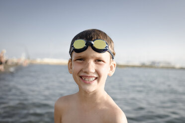 Porträt eines glücklichen Jungen mit Schwimmbrille am Meer - EYAF00115