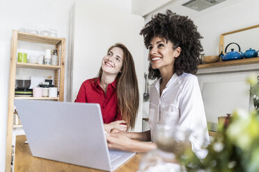 Zwei Frauen arbeiten zusammen in der Küche und benutzen einen Laptop - GIOF06131