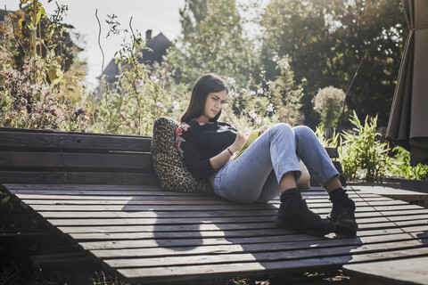 Frau entspannt im städtischen Garten und schreibt in ein Notizbuch, lizenzfreies Stockfoto