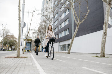 Couple riding e-bikes in the city - JRFF02892