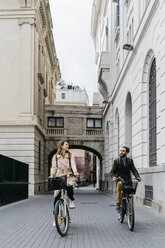 Lächelndes Paar auf E-Bikes in der Stadt - JRFF02902