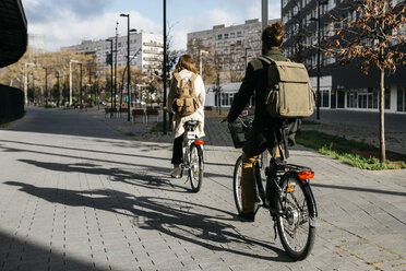 Pärchen auf E-Bikes in der Stadt, Rückansicht - JRFF02904