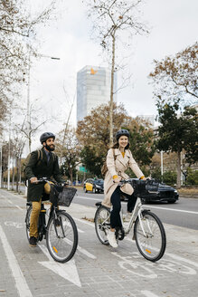 Couple riding e-bikes in the city on bicycle lane - JRFF02909