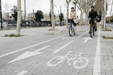 Ein Paar fährt mit einem E-Bike in der Stadt auf dem Fahrradweg - JRFF02911