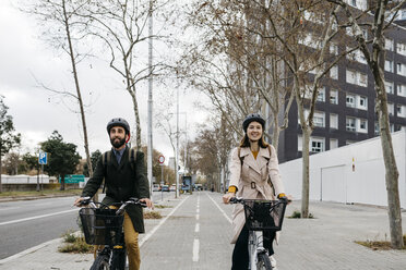 Couple riding e-bikes in the city - JRFF02913