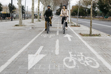 Ein Paar fährt mit einem E-Bike in der Stadt auf dem Fahrradweg - JRFF02914