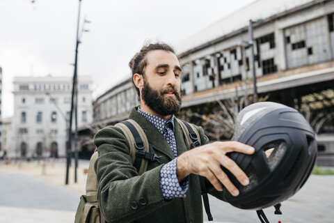 Porträt eines Mannes, der in der Stadt einen Fahrradhelm aufsetzt, lizenzfreies Stockfoto