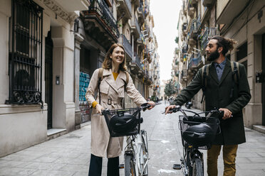 Couple pushing e-bikes exploring the city - JRFF02920