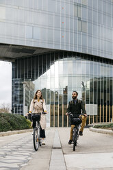 Couple riding e-bikes in the city - JRFF02924