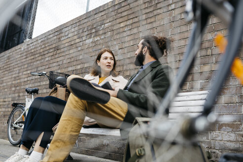 Ehepaar sitzt auf einer Bank neben E-Bikes und unterhält sich - JRFF02932
