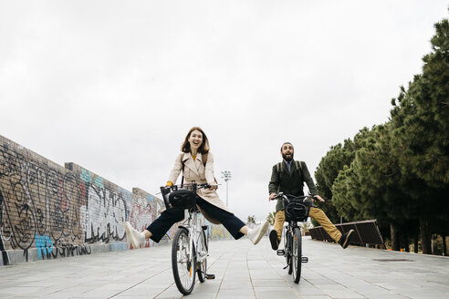 Unbeschwertes Paar fährt mit E-Bikes auf einer Promenade - JRFF02934