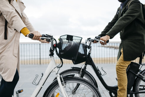 Nahaufnahme eines Paares mit E-Bikes auf der Strandpromenade - JRFF02935