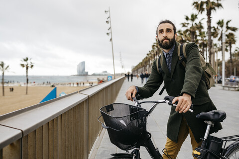 Man with e-bike having a break on beach promenade stock photo