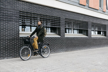 Mann fährt mit dem E-Bike entlang einer Mauer in der Stadt - JRFF02953