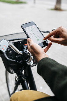 Nahaufnahme eines Mannes mit E-Bike und Smartphone-Navigationssystem - JRFF02958