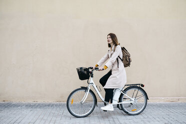 Frau fährt E-Bike entlang einer Mauer - JRFF02973