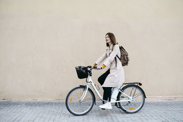 Woman riding e-bike along a wall - JRFF02973