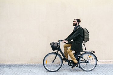 Mann fährt E-Bike entlang einer Mauer - JRFF02974