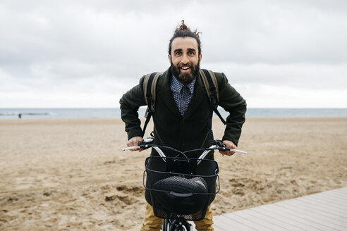 Porträt eines glücklichen Mannes mit E-Bike am Strand - JRFF02977