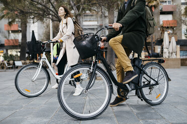 Couple riding e-bikes in the city - JRFF02983