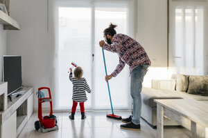 Vater und kleine Tochter putzen gemeinsam das Wohnzimmer - JRFF02984