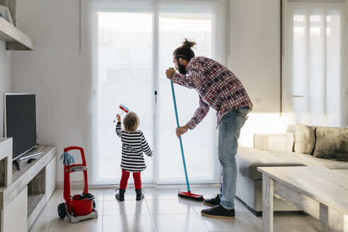 Father and little daughter cleaning the living room together - JRFF02984