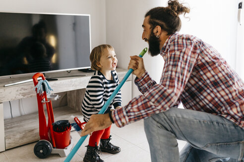 Vater und kleine Tochter haben Spaß zusammen beim Aufräumen des Wohnzimmers - JRFF02986