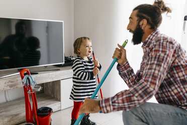 Vater und kleine Tochter haben Spaß zusammen beim Aufräumen des Wohnzimmers - JRFF02987