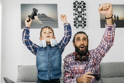Portrait of father and son playing computer game at home stock photo