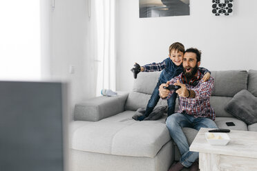 Excited father and son playing computer game at home - JRFF03001