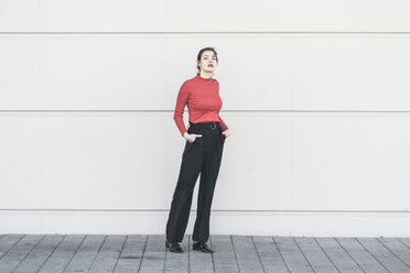 Elegant young woman standing at a wall - UUF17030