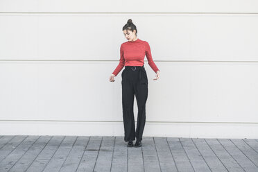 Elegant young woman standing at a wall - UUF17031