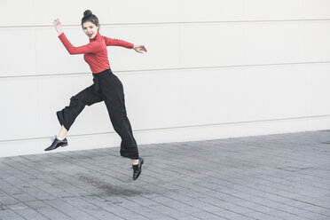 Elegante junge Frauen springen vor einer Mauer - UUF17039