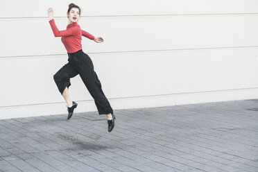 Elegante junge Frauen springen vor einer Mauer - UUF17040