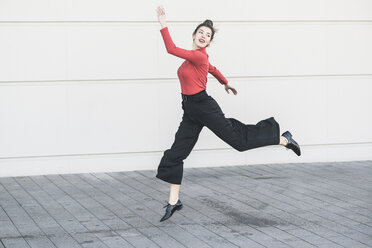 Elegante junge Frauen springen vor einer Mauer - UUF17041