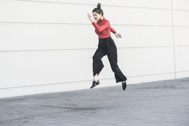 Elegante junge Frauen springen vor einer Mauer - UUF17042