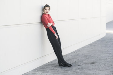 Elegant young woman leaning against a wall - UUF17044