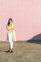Selbstbewusste junge Frau vor einer rosa Wand stehend - UUF17063
