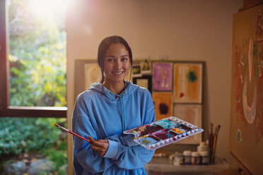 Portrait smiling female artist painting in art studio - HOXF04324