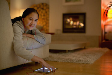 Portrait smiling young woman listening to music with headphones and digital tablet - HOXF04357